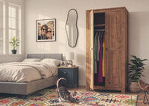 Chat qui s&rsquo;&eacute;tire sur le sol d&rsquo;une chambre avec armoire en bois et meubles de rangement.