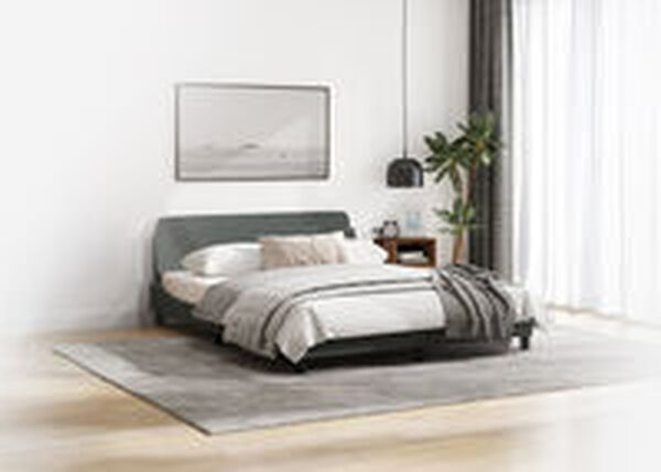 Int&eacute;rieur de chambre minimaliste avec un lit bas gris fonc&eacute;, du linge de lit gris clair, un grand tableau encadr&eacute; repr&eacute;sentant un paysage au-dessus de la t&ecirc;te de lit, une table de chevet en bois et une plante en pot. Un tapis gris est pos&eacute; sur un sol en bois clair, avec des voilages blancs en arri&egrave;re-plan.